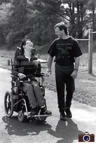 photo of a man walking next to a man in a wheelchair