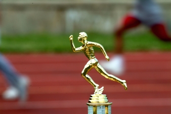photo of a runners trophy next to a running track